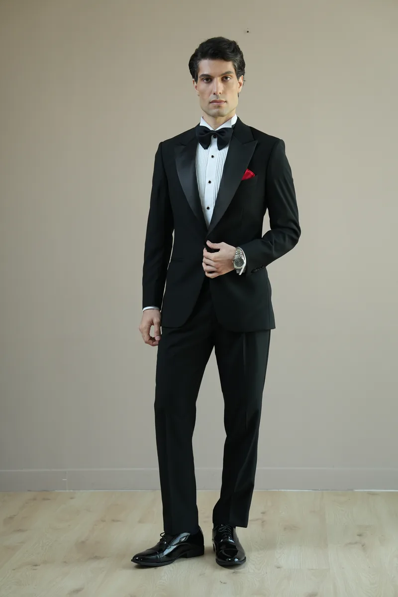 Black bespoke tuxedo with satin lapels, black bow tie and a red pocket square for a black-tie event in Dubai