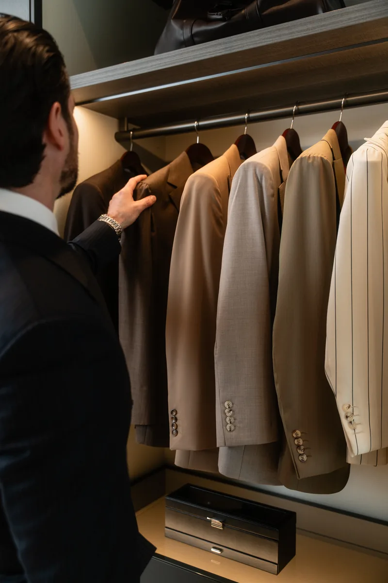 Choosing jackets from a rail of cream, taupe and brown tailoring for a wedding party