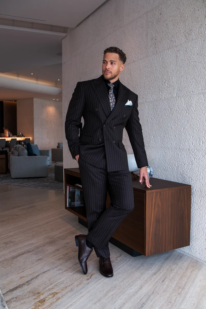 Man in a dark pinstripe bespoke suit at home in Dubai, fitted through The Moving Tailor home tailor service